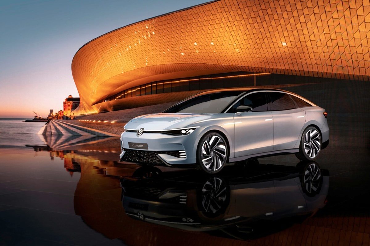 Futuristic Volkswagen ID. Aero electric sedan at dusk in front of a glowing modern building